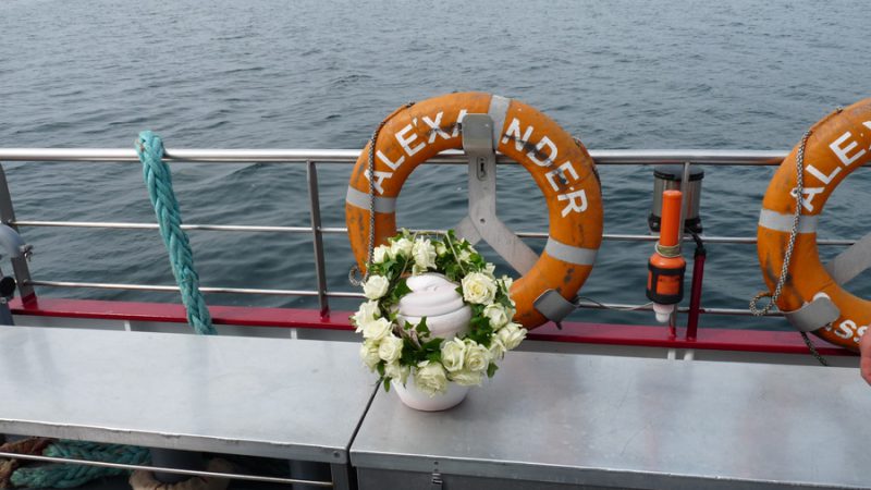 Bestattungsurne von Seebestattung Rügen mit weißen Blumen am Board der MS Alexander